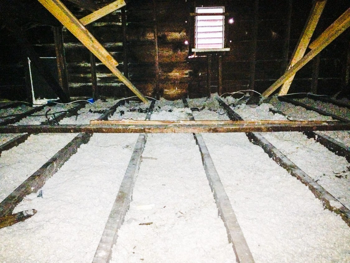 Attic before a MyGreenKC blown-in insulation top-up, with thin old insulation between the joists